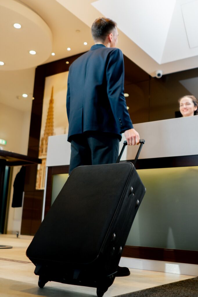 The receptionist at counter meets the guest with luggage in the hotel business travel hospitality